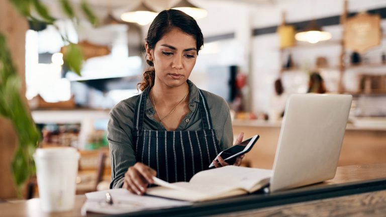 Cafe owner reviewing local search signals on a laptop and phone