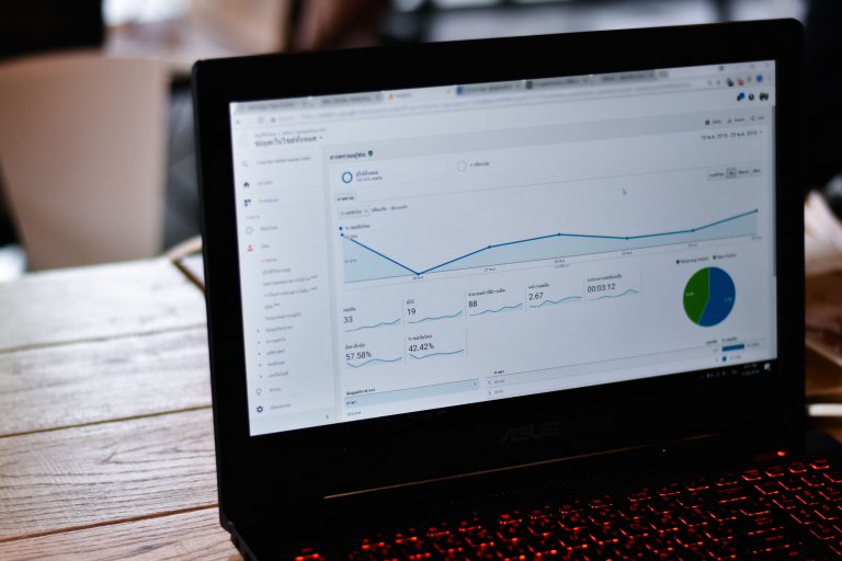 Laptop on a desk showing a Google Search Console performance dashboard with a rising branded-search line chart, representing a small business owner measuring AI search visibility through branded-search lift.