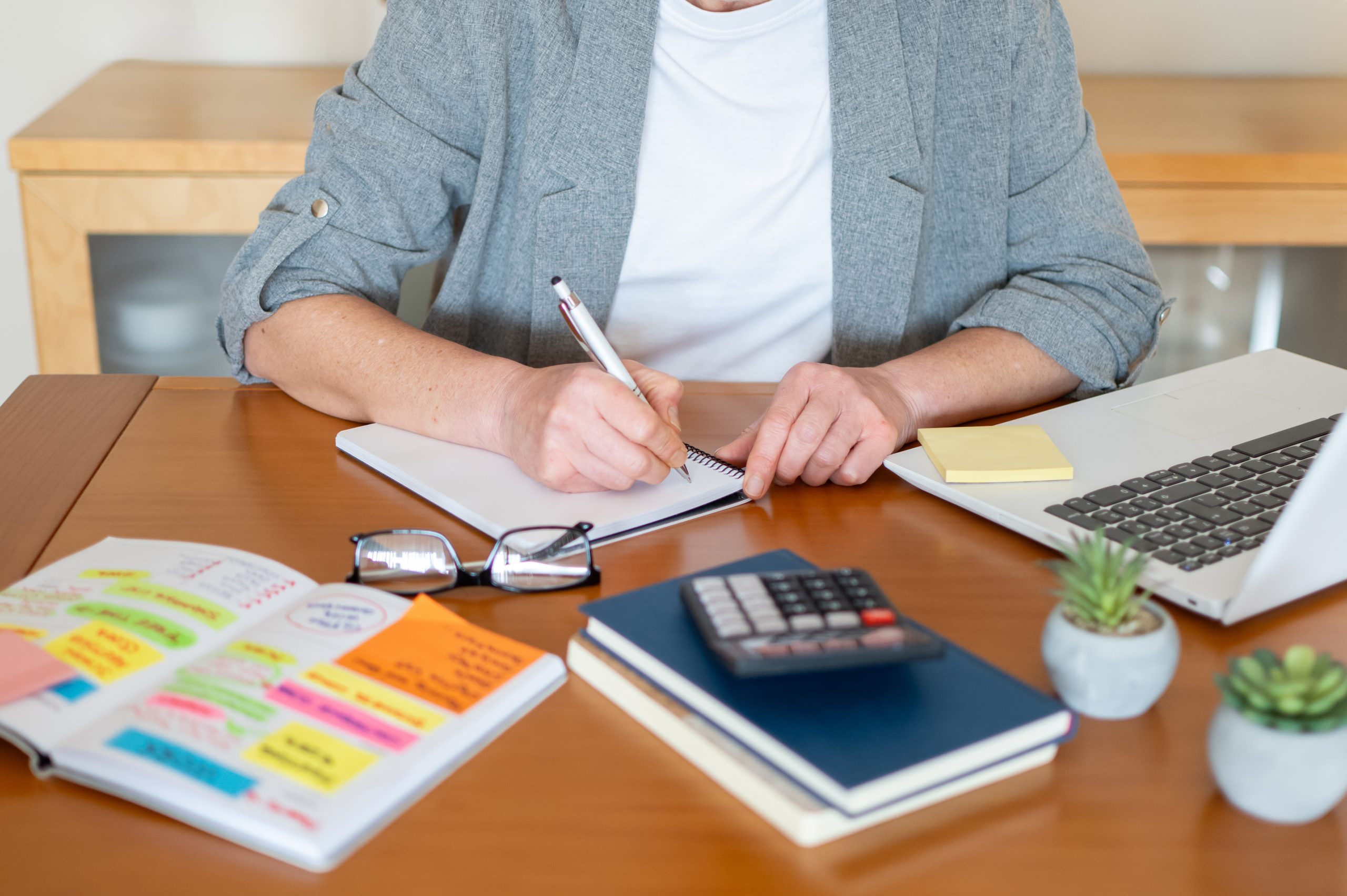 Small business owner comparing SEO pricing tiers on a laptop and proposal printouts at a Treasure Coast desk, with budget worksheet and calculator visible, illustrating how to read affordable SEO quotes against monthly scope.