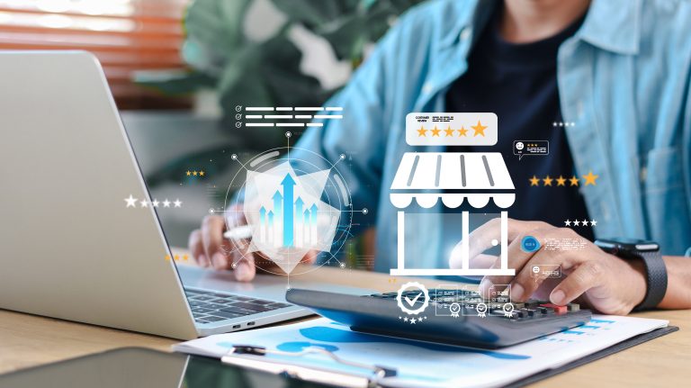 Small business owner at a wooden desk reviewing a laptop dashboard showing storefront, five-star ratings, and visitor analytics overlays.