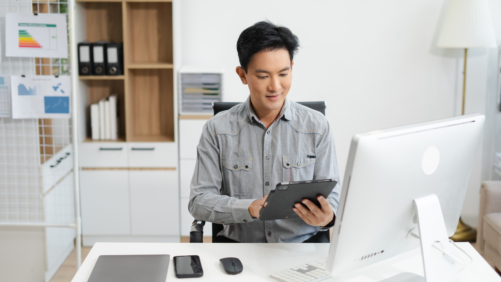 Mature small business owner sitting at a laptop in his office, thinking through a strategy decision about outsourcing.
