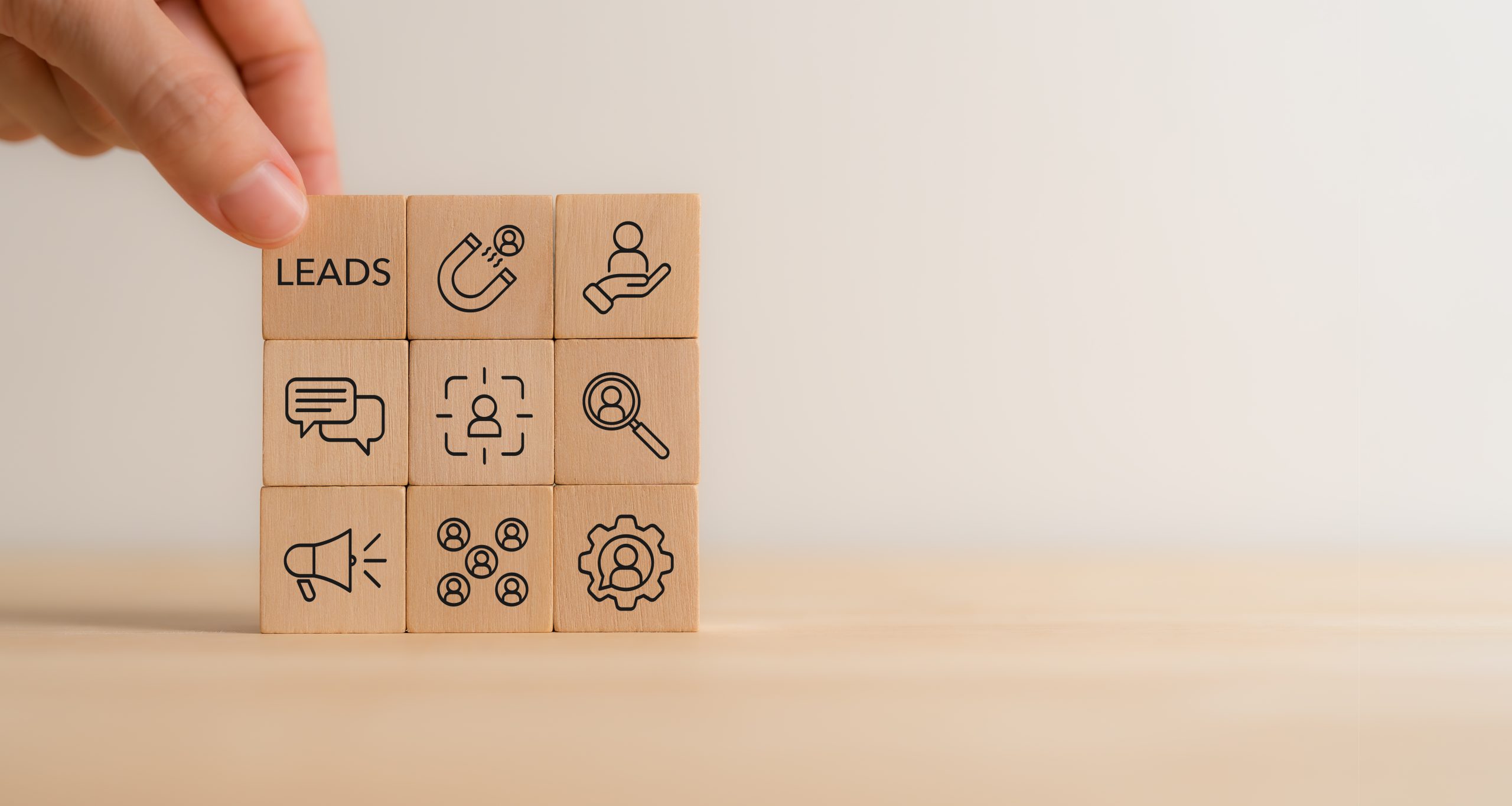 Conceptual illustration of small business lead generation: wooden blocks arranged on a desk with icons for leads, customer attraction, conversation, audience targeting, and process automation, representing the steps a blog content strategy needs to turn readers into qualified inquiries.