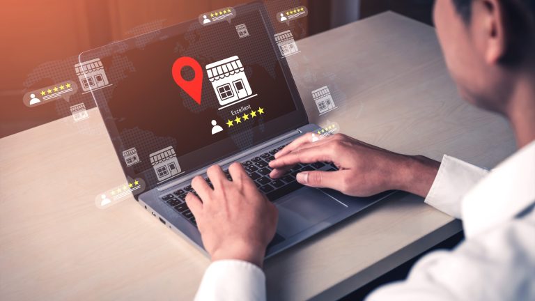 Small business owner reviewing customer reviews and location data on a laptop while deciding whether to send an AI-drafted reply.