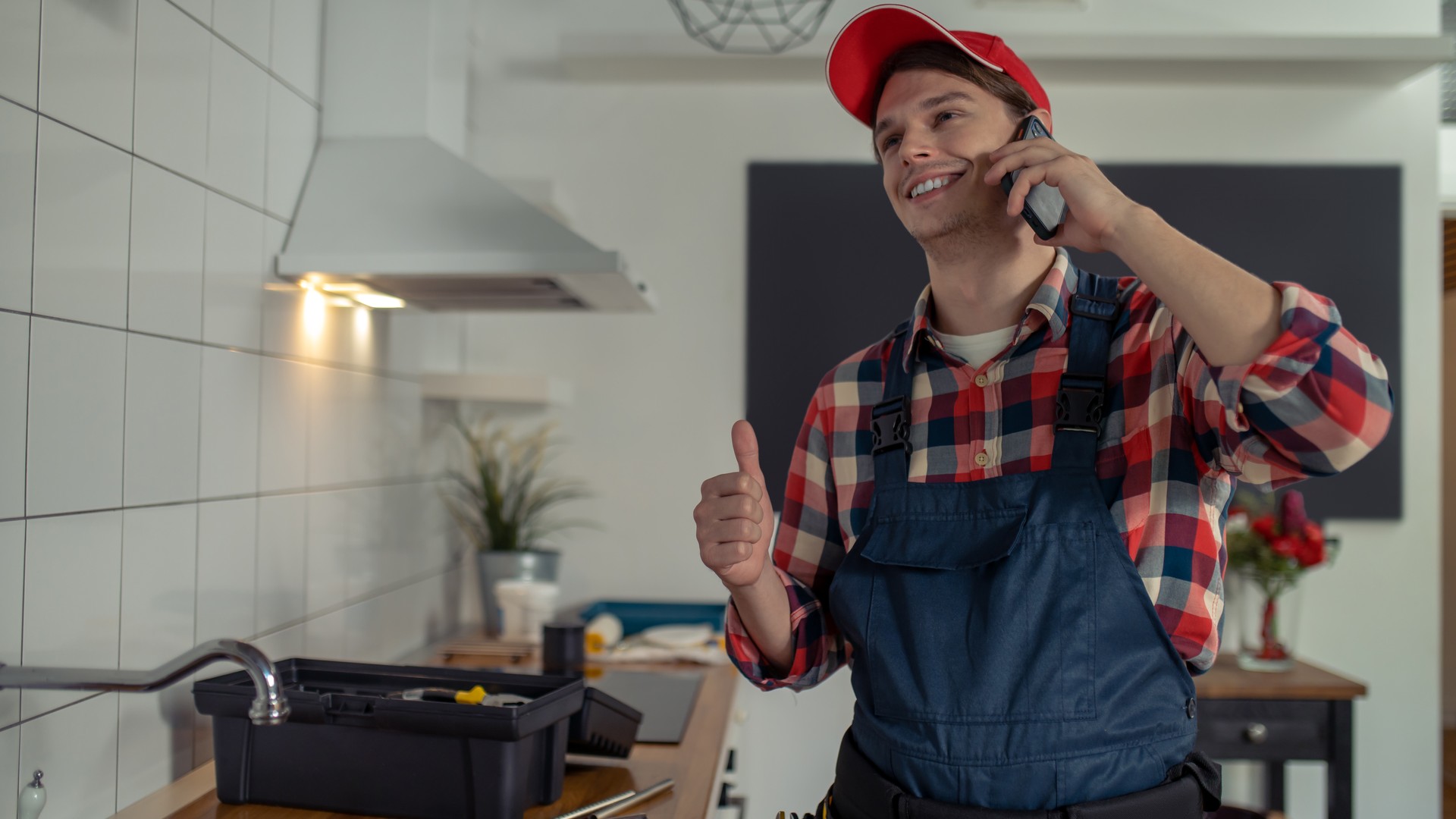 Local service technician in a work uniform smiling while taking a customer phone call near a work van