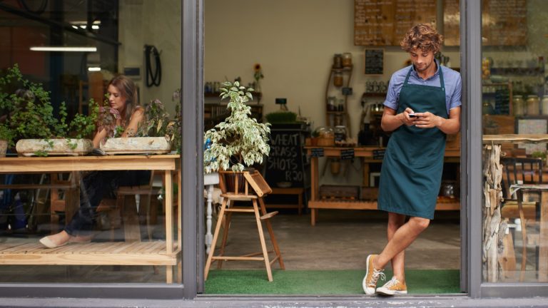 Small business owner standing in his shop entrance, wondering where his local customers are