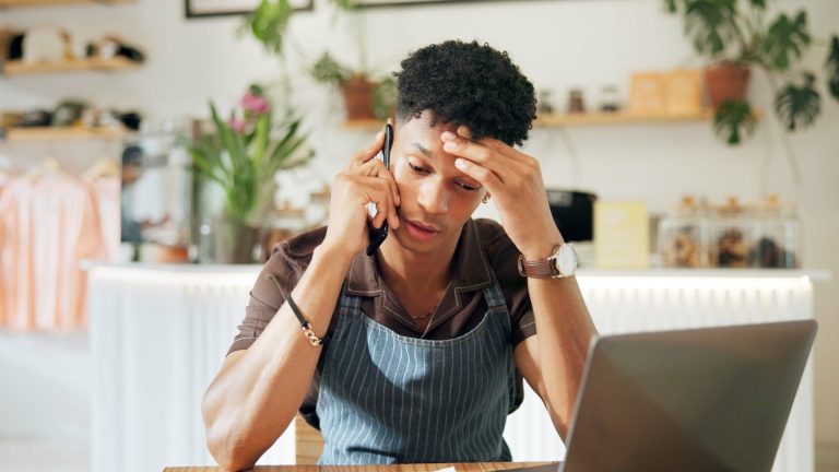 Small-business owner reviewing a missed Local Services Ads call beside a laptop