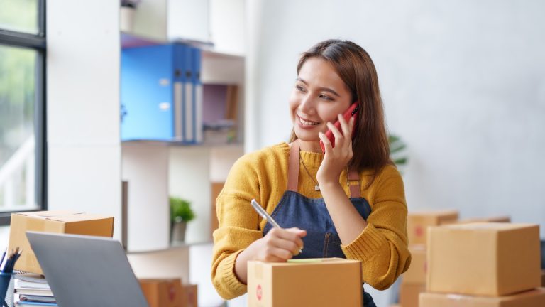 Small business owner taking notes while speaking on a mobile phone
