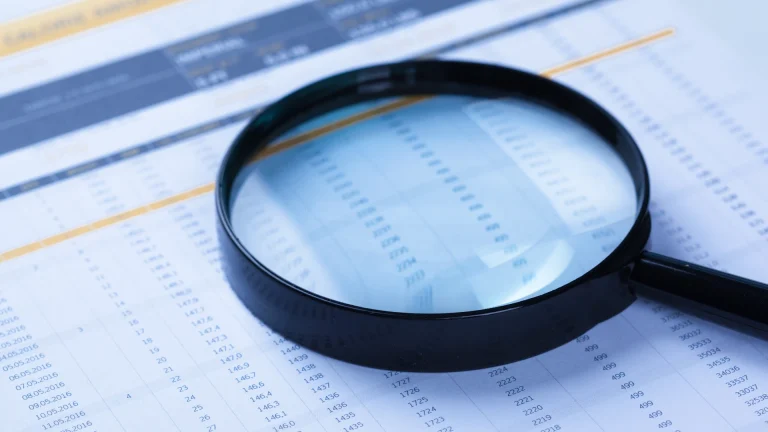 Magnifying glass over rows of numbers on a printed data report